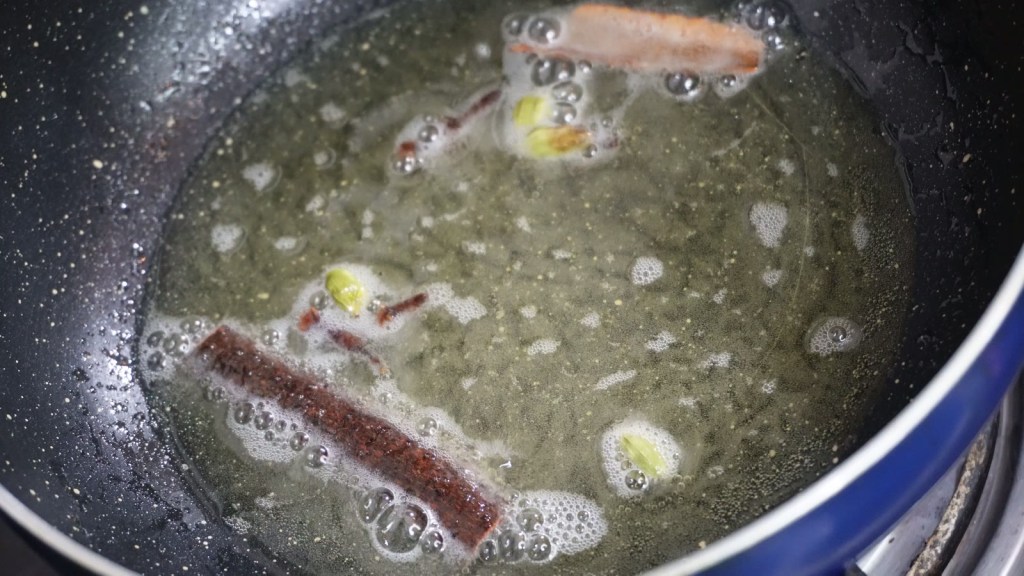 गरम तेलात दालचिनी, वेलची आणि लवंग परतणे